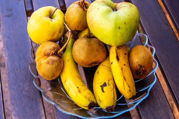 Conjunto de frutas en un plato de cristal sobre una mesa de madera