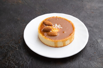 Sweet tartlets with almonds and caramel cream on a black concrete background. side view.