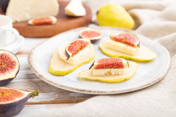 Summer appetizer with pear, cottage cheese, figs and honey on a white wooden background. Side view, selective focus.
