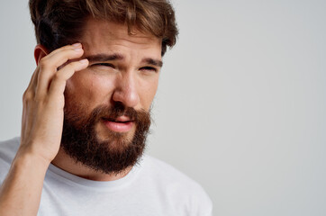 man in a white t-shirt headache migraine problems light background
