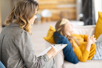 Teenage depression. Psychologist working with teen girl at office, talking to her patient, taking...
