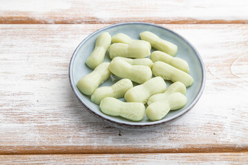 Jelly celery candies on white wooden background. side view.