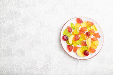 Various fruit candies on plate on gray concrete background. copy space, top view.