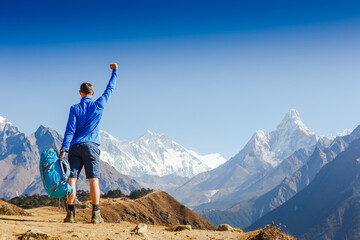 Hiker cheering elated and blissful with arms raised in the sky after hiking. Everest mountain on the backgroung - the world highest peak