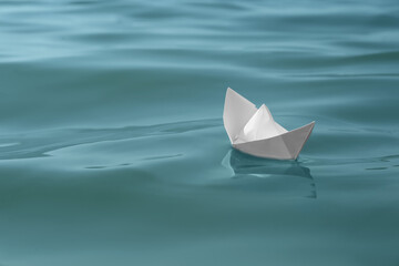 White paper boat floating on water surface, space for text