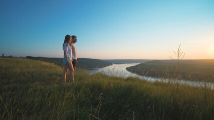 The romantic couple standing on a mountain top on a beautiful river background
