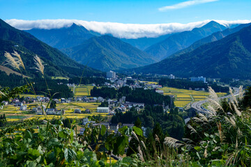 岩原高原から眺める米処新潟県湯沢町の秋の田園風景と山を覆う滝雲