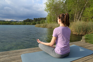 Yogi practicing yoga exercise in a lake pier