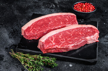 Fototapeta na wymiar Raw cap rump steak or top sirloin beef meat steak on marble board. Black background. Top view