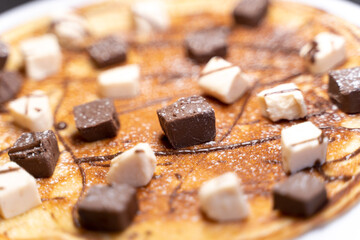 Focus on dark and white chocolate shavings on top of a pancake