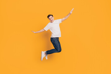 Portrait of crazy inspired guy jump make plan figure hands wings on yellow background