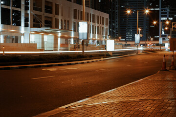 Empty asphalt road with modern buildings at night in Dubai