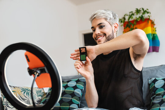 Transgender streaming online make up video tutorial with mobile phone indoors at home - Lgbt, gay, technology trendy concept - Focus in face