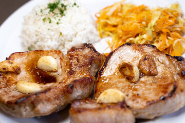 Close up view of a grilled meat with plain rice and vegetables
