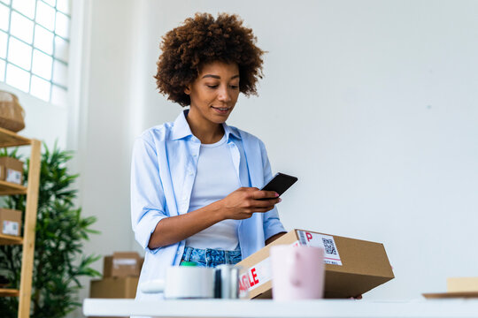 Young woman scanning barcode through smart phone at studio