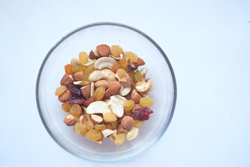 close up of many mixed nuts in a bowl on white 