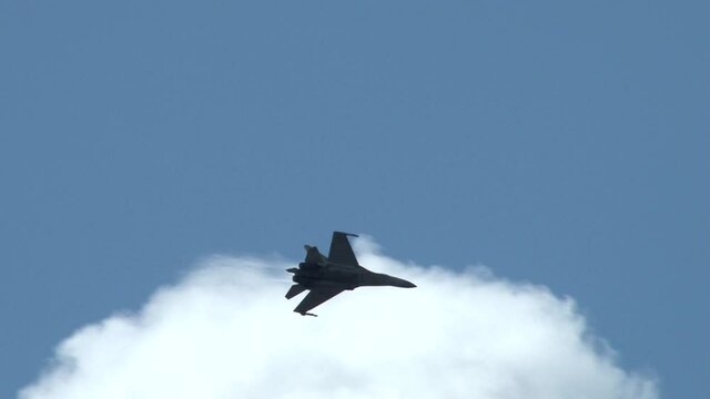 Multipurpose fighter Su-35 (Flanker-E) with nozzles with deflected thrust vector performs aerobatics in the sky with clouds. Close-up. Zhukovsky, Russia, August 9, 2012.
