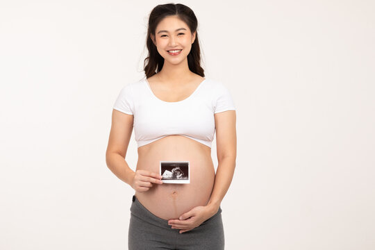 Happy Pregnant Woman standing smile holding ultrasound image stroking big belly with love isolated on white background,Pregnancy of young woman enjoy with future life,Motherhood and Pregnant Concept