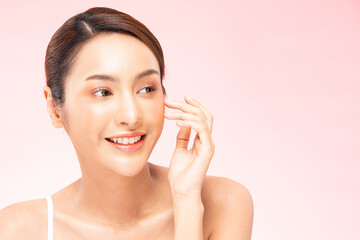 Young Beautiful Asian woman smile touching soft cheek with clean and fresh skin Happiness and cheerful with positive emotional,isolated on pink background,Beauty Cosmetics and spa Treatment Concept