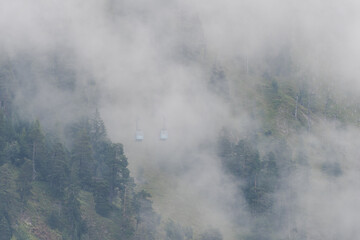 The two cable cars of the Herzogstandbahn in Bavaria passing each other on cold misty day with clouds and fog