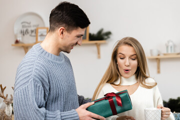 Sweet couple opening Christmas gifts in the living room at home