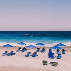 Beach with sand, blue sunbeds and sea. Retro styled concept