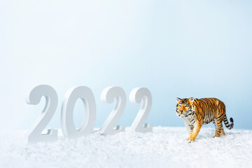 Happy New Year 2022. Decorative white number 2022 and figurine of tiger isolated on blue background. Christmas greeting card.