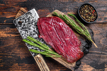 Venison raw meat steak on a cuuting board with rosemary. Black background. Top view - obrazy, fototapety, plakaty