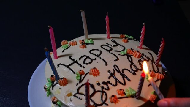 Lady lit birthday cake candles on the table