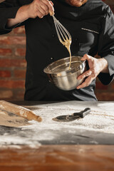 Fototapeta premium Cropped image of male chef, cook in black kitchen uniform make bread dough at cafe, restaurant kitchen. Concept of healthy diet, national cuisine.