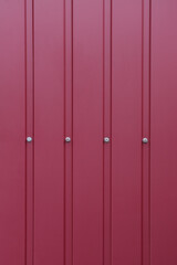 Fototapeta premium Profiled red screwed on the screws. Fragment of a wall made of red profiled metal sheet.