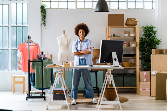 Confident female fashion designer with arms crossed standing at studio