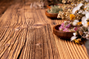 Obraz na płótnie Canvas Natural medicine background. Assorted dry herbs in bowls and brass mortar on rustic wooden table.