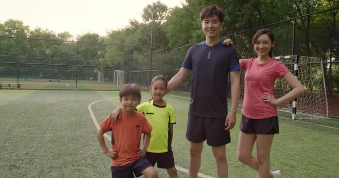 Happy young family playing football on soccer field,4K