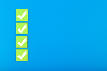 Four checkmarks on green tablets in a row on blue background with copy space. Concept of...