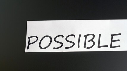 cutting word IMPOSSIBLE to read POSSIBLE. Female hand using scissor to express motivation and encouragement objective. Concept of think positive, self belief and success of achievement