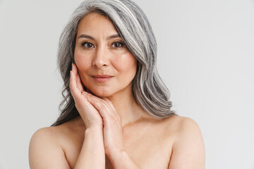 Mature shirtless woman with grey hair posing and looking at camera