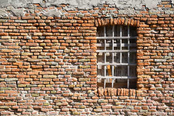 Boarded up window with wooden bars in an old shabby brick house