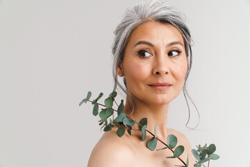 Mature shirtless woman with grey hair posing with eucalyptus © Drobot Dean