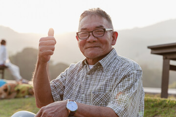 Asian old man sitting and relaxing in public park.
