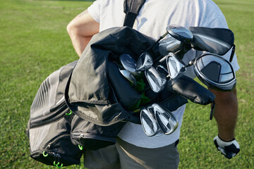 Golfer with carrying bag behind with different golf clubs on the golf course while playing golf...
