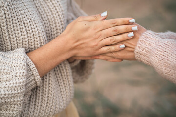 The girls are frozen for walks and warming their hands. A friend warms her hands. Close-up of the hands of two girls. The girl blows warm air on her hands to keep warm