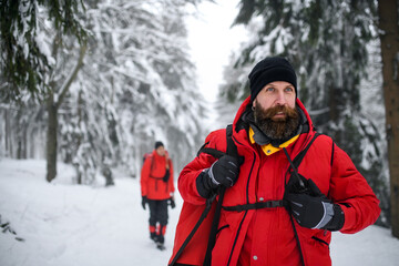 Fototapeta na wymiar Paramedic man from mountain rescue service with walkie talkie outdoors in winter in forest.