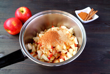 Unrefined sugar and ground cinnamon added into the pot of diced apples for making apple compote	