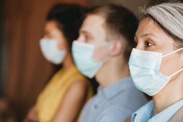 Man and women in face mask looking aside while standing by wall