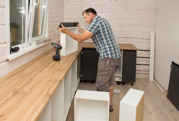 Furniture assembler assembles modern kitchen furniture in a private home