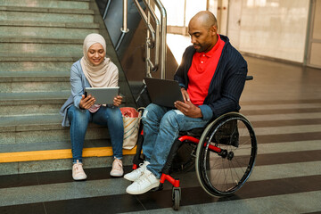 Obraz premium Muslim woman and disabled man using gadgets together