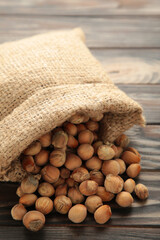 Hazelnuts, filbert in burlap sack on brown wooden backdrop. Hazelnut background, healty food. Vertical photo