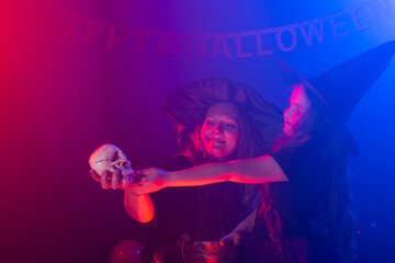 Funny child girl and woman in witches costumes for Halloween.