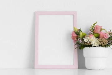 Pink frame mockup with a bouquet of roses on the white table.